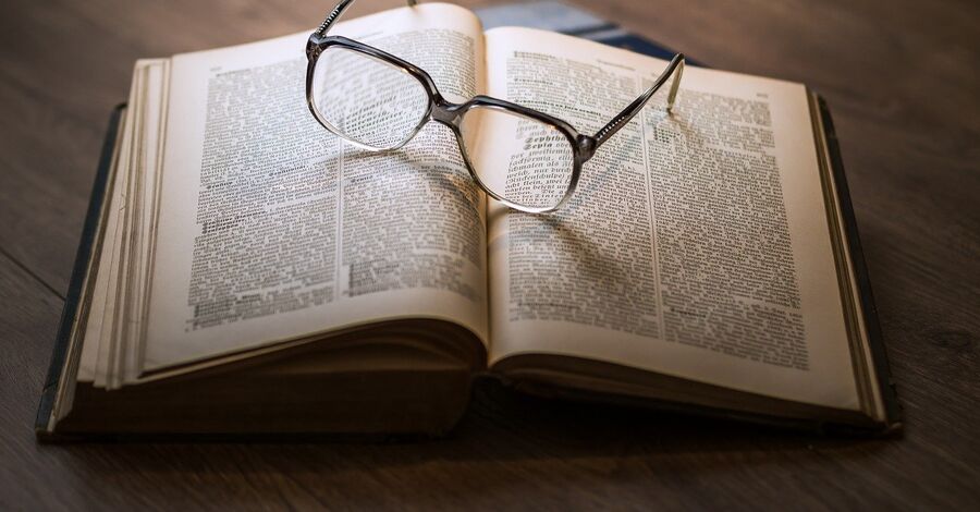 un libro abierto con lentes apoyados sobre las páginas